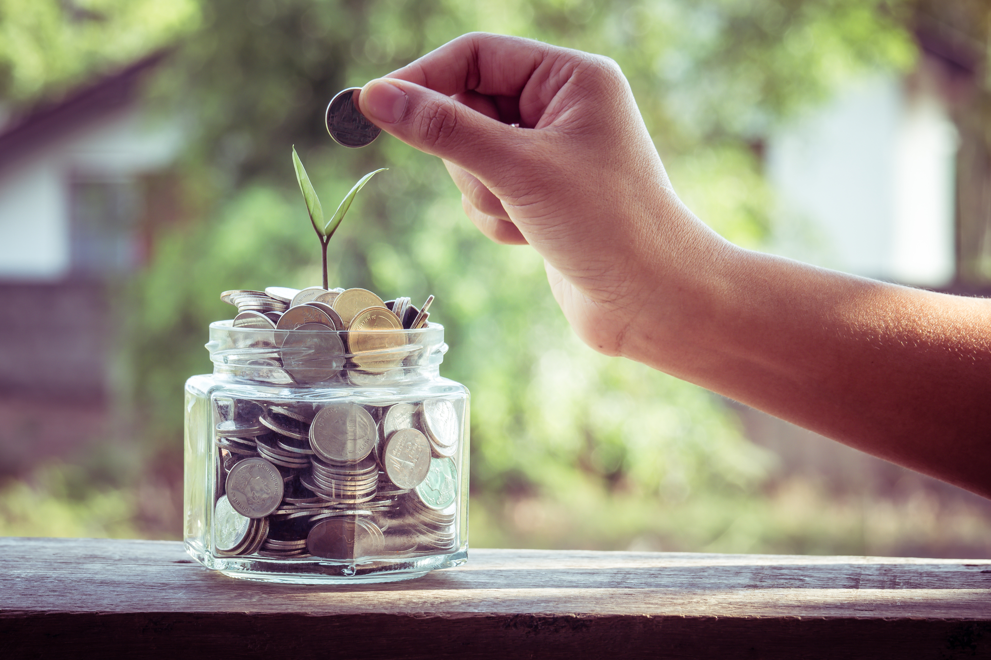 hand putting money coins with filter effect retro vintage style